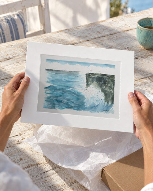 La Costa Brava, mar y acantilado, acuarela original con passepartout blanco recién desembalada sobre una mesa de madera
