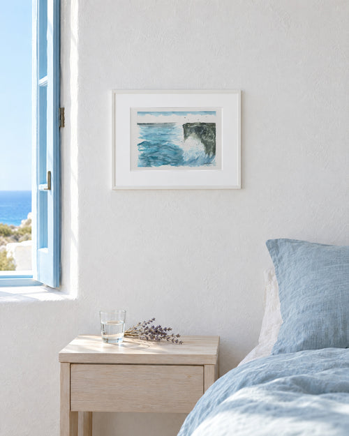 La Costa Brava, mar y acantilado, acuarela original enmarcada en blanco en un dormitorio con ropa de cama de lino azul
